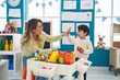 © Krakenimages.com - Teacher and toddler playing with construction blocks high five at kindergarten