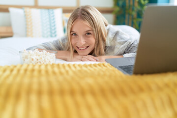 Poster - Young blonde woman watching movie on laptop lying on bed at bedroom