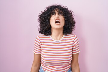 Poster - Young middle east woman standing over pink background angry and mad screaming frustrated and furious, shouting with anger. rage and aggressive concept.