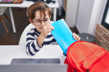 Sticker - Adorable hispanic boy student holding book of backpack at classroom