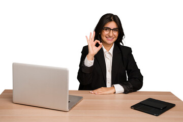 Young indian woman in a table with a laptop and tablet isolated cheerful and confident showing ok gesture.