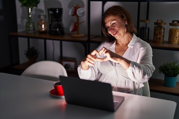 Sticker - Middle age hispanic woman using laptop at home at night smiling in love doing heart symbol shape with hands. romantic concept.