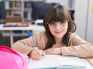 Poster - Adorable hispanic girl student sitting on table doing homework at classroom