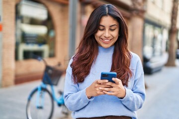 Wall Mural - Young hispanic woman smiling confident using smartphone at street