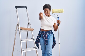 Canvas Print - African american woman holding roller painter pointing displeased and frustrated to the camera, angry and furious with you