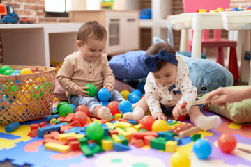 Poster - Two toddlers playing with balls and xylophone sitting on floor at kindergarten