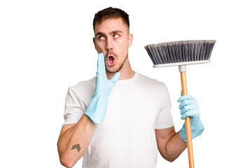 Wall Mural - Young man holding a broom to clean his house cut out isolated is saying a secret hot braking news and looking aside