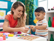 © Krakenimages.com - Teacher and toddler playing with maths puzzle game sitting on table at kindergarten