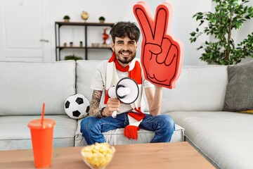 Young hispanic hooligan man supporting soccer team at home