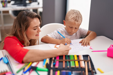 Poster - Teacher and toddler sitting on table drawing on paper at classroom