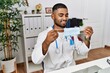 © Krakenimages.com - Young arab man wearing doctor uniform holding medical mask at clinic