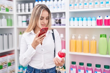 Wall Mural - Young blonde woman customer make phot by smartphone to medicine bottle at pharmacy