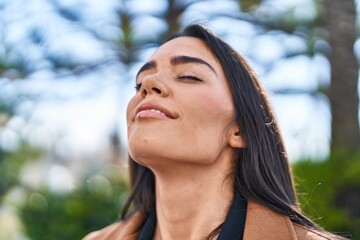 Wall Mural - Young hispanic woman smiling confident breathing at park