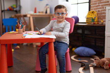 Sticker - Adorable hispanic toddler student smiling confident drawing on notebook at classroom