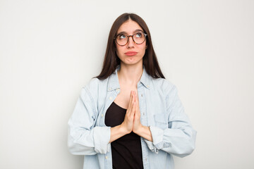 Young caucasian woman isolated on white background holding hands in pray near mouth, feels confident.