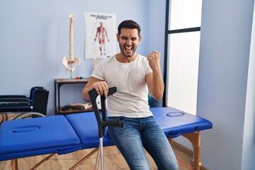 Sticker - Young hispanic man with beard wearing crutches at rehabilitation clinic annoyed and frustrated shouting with anger, yelling crazy with anger and hand raised