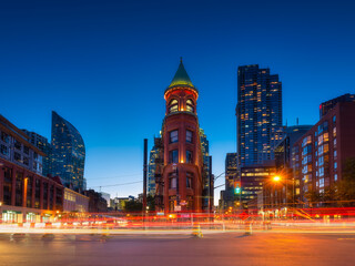 Canada, Toronto. The famous Gooderham building and the skyscrapers in the background. View of the city in the evening. Blurring traffic lights. Modern and ancient architecture. Night city.