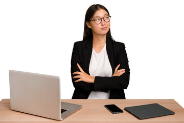 Young business asian woman sitting on a table isolated dreaming of achieving goals and purposes