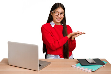 Wall Mural - Young student asian woman in a workplace with a laptop isolated holding a copy space on a palm.