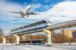 View railway track suburban electric monorail train rushing departure area airfield. Passenger plane jet flying sky, take off airport winter snow. Concept city modern infrastructure transport travel.
