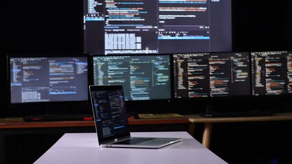 A Laptop'S Monitor Showing Code On The Table In Front Of Multiple Monitors With Database On Terminal Window Desktops In The Office
