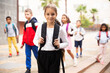© JackF - Portrait of tweenager girl with backpack walking with other schoolchildren to school campus after lessons on warm fall day.