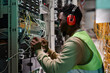 © Seventyfour - Side view portrait of young technician setting up network in server room and wearing protective workwear