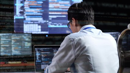 Back View Of Asian Male Programmer Writing Code By A Laptop Using Multiple Monitors Showing Database On Terminal Window Desktops In The Office. Code Animation Footage
