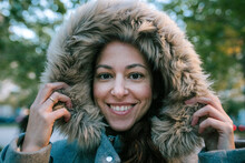 Close-up Portrait Of Happy Woman Wearing Fur Coat While Standing Against Trees In Park