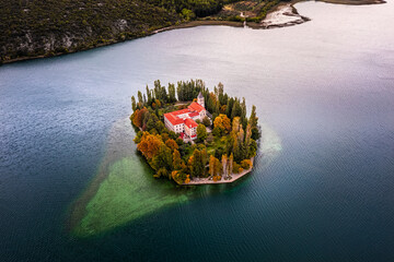 Wall Mural - Visovac, Croatia - Aerial view of the beautiful island Visovac Christian monastery in Krka National Park on a bright autumn morning with autumn foliage and blue water