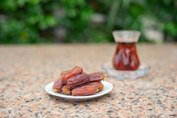 Wall Mural - Dry Dates in a bowl and tea in armudu glass. Ramadan kareem.  Outdoor  background.