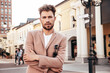 © halayalex - Handsome confident stylish hipster model.Sexy modern man dressed in elegant beige suit. Fashion male posing in the street background in Europe city at sunset