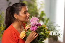 Close-up Portrait Of A Young Woman With Eyes Closed Holding Flower Bouquet And Smelling