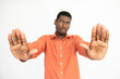 © KAMPUS - Close-up of male hands making stop gesture over white background. African American guy wearing orange T-shirt showing forbiddance sign. Restriction concept