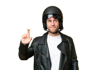 Wall Mural - Young caucasian man with a motorcycle helmet isolated on green chroma background with fingers crossing and wishing the best