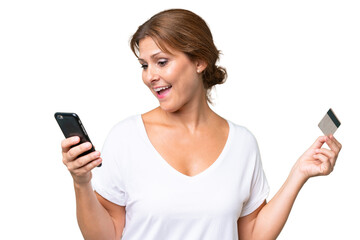 Middle-aged caucasian woman over isolated background buying with the mobile with a credit card