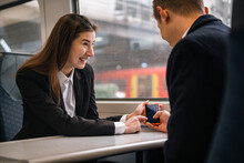 Happy Businesswoman Pointing And Sharing Smart Phone To Colleague In Train