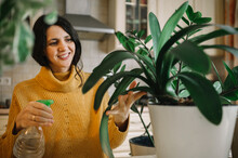 Happy Woman Spraying Water On Plant