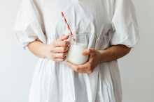 Woman Holding Jar Of Milkshake With Straw In Front Of Wall
