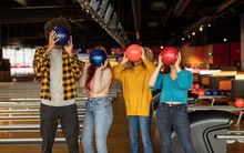 Friends Covering Face With Balls At Bowling Alley