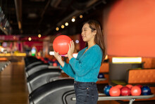 Young Woman Holding Bowling Ball At Alley