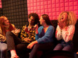© Westend61 - Happy young friends holding microphone sitting on sofa at amusement arcade