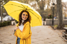 Happy Beautiful Woman With Yellow Umbrella Standing At Footpath