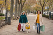© Westend61 - Happy senior woman holding shopping bags walking with granddaughter and dog at footpath