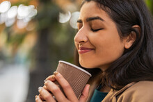 Smiling Woman With Eyes Closed Holding Disposable Coffee Cup