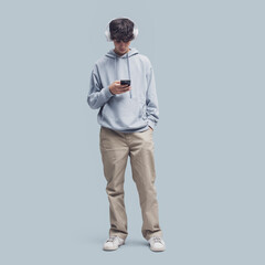 Wall Mural - Teenager standing and using a smartphone