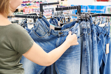 Poster - Buyer woman chooses jeans in store