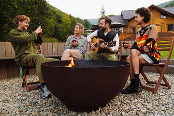 Wall Mural - Multinational people drinking tea and taking photo around campfire