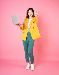 Wall Mural - Full length image of young Asian bussinesswoman holding laptop on background