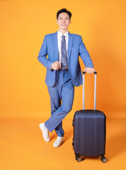 Wall Mural - Image of young Asian business man holding suitcase on background